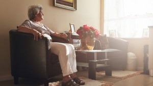 Mulher idosa sentada em sala com luminosidade da janela, representando possibilidade de que almas nos visitem