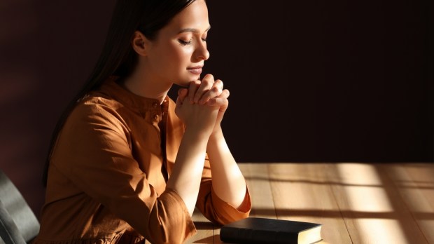 kobieta modli się z Pismem Świętym przy stole