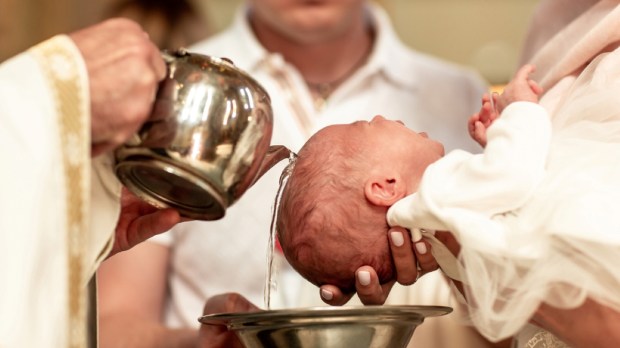 Padrinho de batismo assiste ao batizado de um bebê