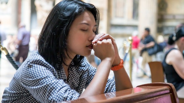 Mulher rezando na Igreja simboliza a busca pelo olhar de Jesus