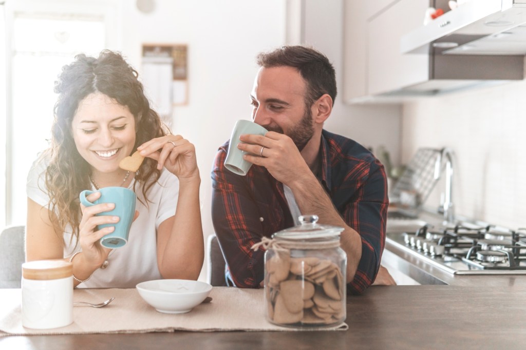 małżeństwo rozmawia w kuchni popijając kawę i ciesząc się byciem razem