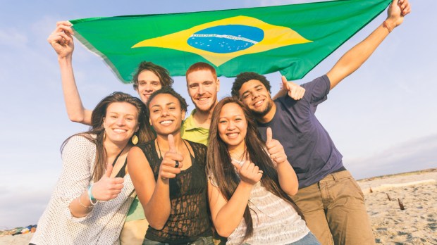 Jovens brasileiros com bandeira na praia
