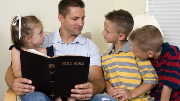 pai lê a Bíblia com os filhos