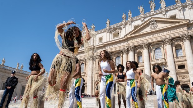A group of Brazilian faithfuls dress in traditional clothes perform a dance as Pope Francis arrives for his weekly general audience