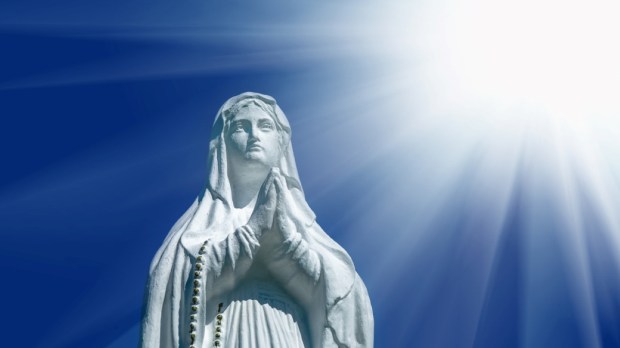 Virgin Mary statue. Vintage sculpture of sad woman in sunlight