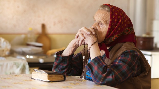 Mulher idosa rezando o terço