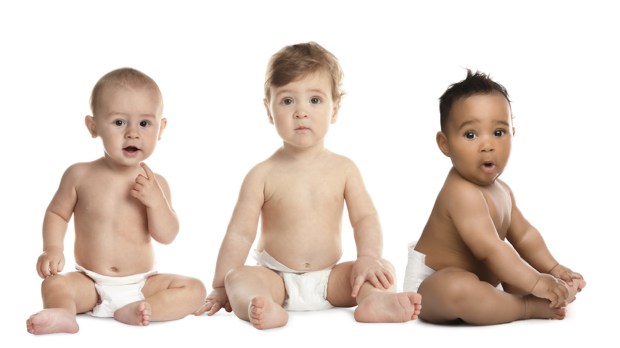 Três bebês sentados, de fraldas e atentos